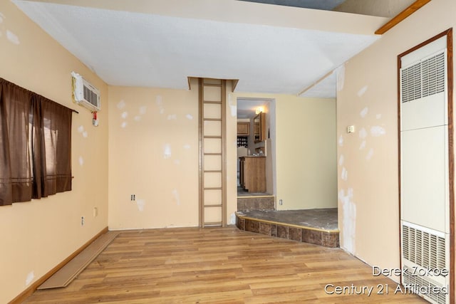 771 Sunny Trl, Greenville, MI 48838 - spare room with a heating unit, wood finished floors, and an AC wall unit