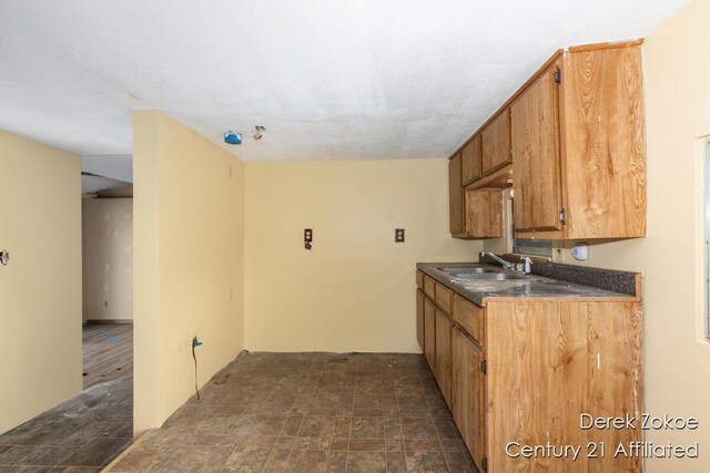771 Sunny Trl, Greenville, MI 48838 - kitchen featuring a sink, stone finish flooring, dark countertops, and brown cabinetry