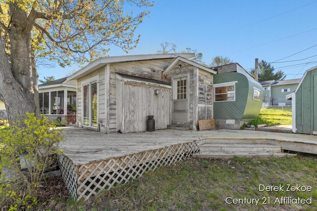 771 Sunny Trl, Greenville, MI 48838 - rear view of property featuring a sunroom, a deck, an outdoor structure, and a shed