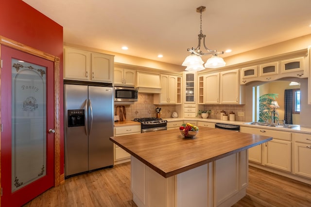 kitchen with stainless steel appliances, butcher block counters, glass insert cabinets, backsplash, and recessed lighting