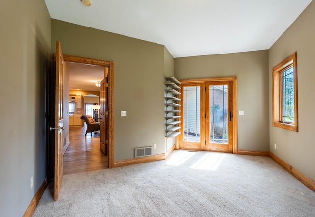 entrance foyer with carpet floors, baseboards, and french doors