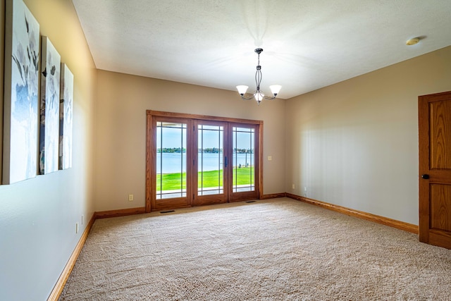 carpeted spare room with a chandelier, baseboards, a water view, and a smoke detector