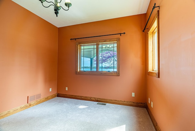 spare room featuring carpet, baseboards, and a chandelier