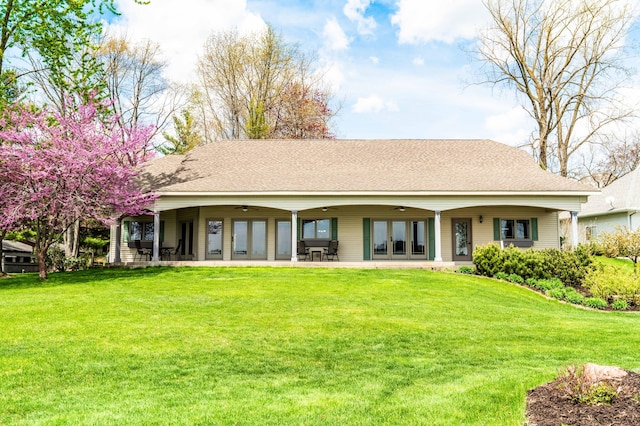 rear view of property with ceiling fan, a yard, a shingled roof, and a patio area