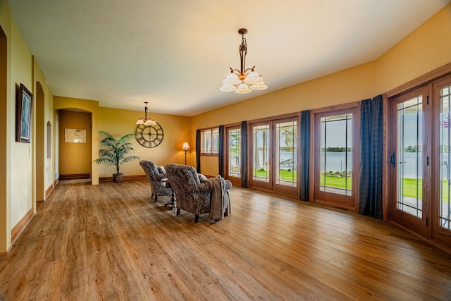 dining room featuring a chandelier, light wood-type flooring, arched walkways, and baseboards