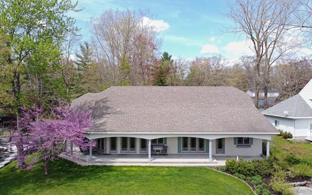 back of house with a lawn, a patio, and a shingled roof