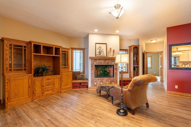living room featuring light wood-type flooring, a fireplace, baseboards, and recessed lighting