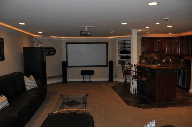 cinema room with bar with sink, dark carpet, recessed lighting, ornate columns, and baseboards