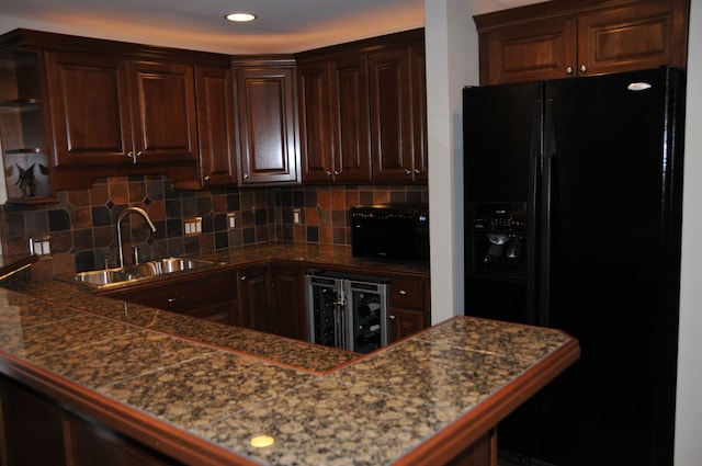 kitchen featuring black appliances, a sink, wine cooler, dark brown cabinets, and decorative backsplash