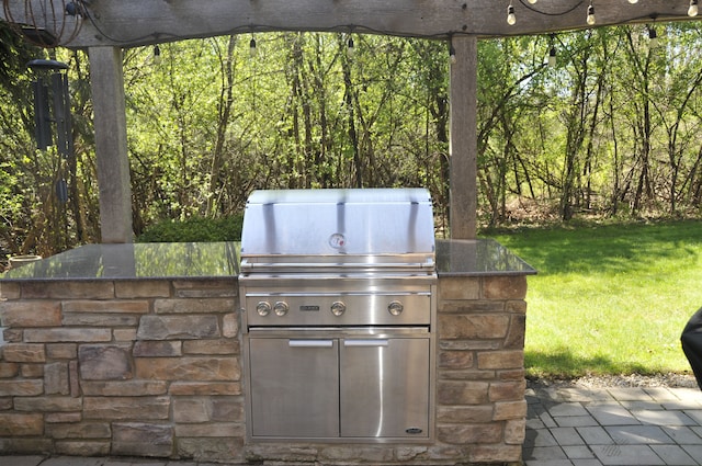view of patio / terrace featuring grilling area, a wooded view, and an outdoor kitchen