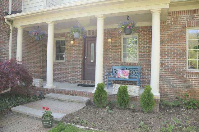 entrance to property with covered porch and brick siding