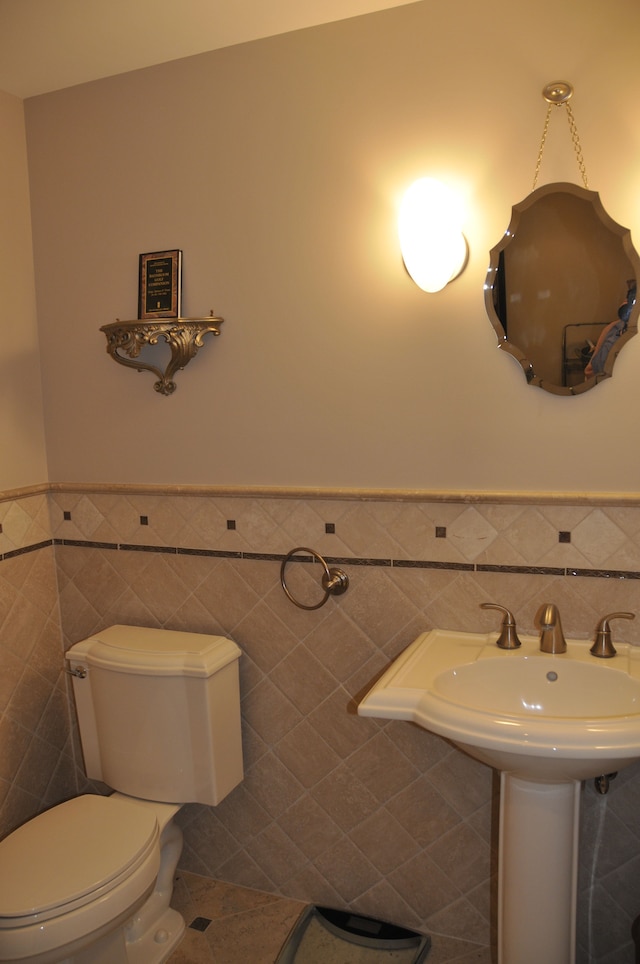 bathroom with tile walls, wainscoting, and toilet