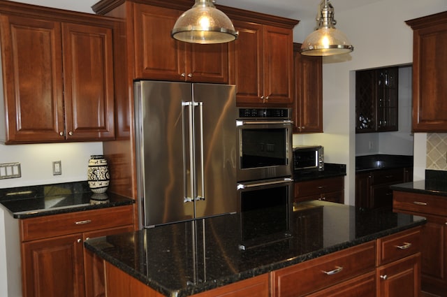 kitchen featuring appliances with stainless steel finishes, decorative light fixtures, decorative backsplash, and a center island