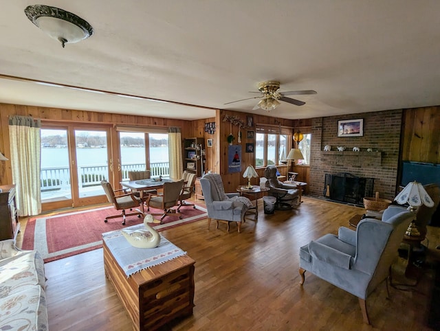 63568 Zabel Shores Rd, Sturgis, MI 49091 - living area featuring wood walls, wood finished floors, a ceiling fan, a fireplace, and a water view