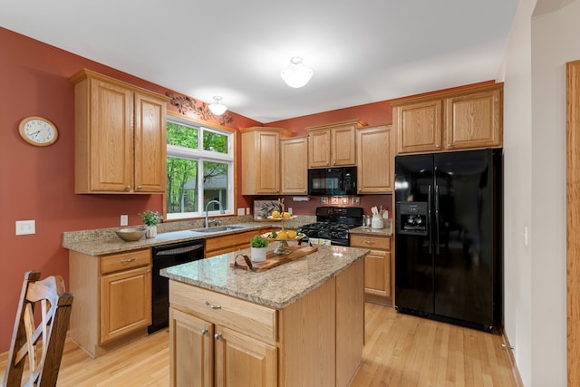 3135 Walnut Hls, Leonard, MI 48367 - kitchen with black appliances, a sink, light wood-type flooring, light stone counters, and a center island