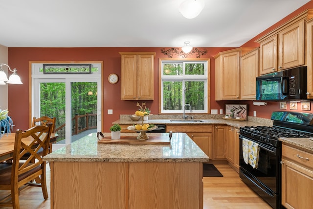 3135 Walnut Hls, Leonard, MI 48367 - kitchen with black appliances, a sink, light wood-type flooring, a center island, and light stone counters