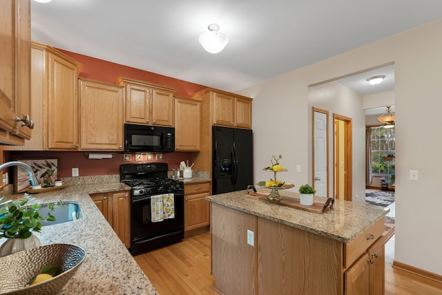 3135 Walnut Hls, Leonard, MI 48367 - kitchen with black appliances, a sink, a center island, light wood-style floors, and light stone countertops