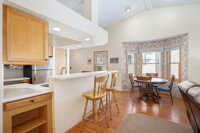 9098 Luea Ln, Swartz Creek, MI 48473 - kitchen featuring lofted ceiling, freestanding refrigerator, a kitchen bar, light wood finished floors, and light brown cabinetry