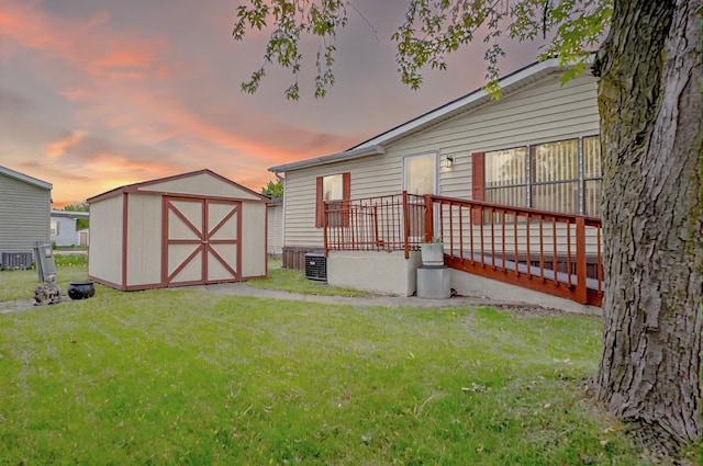 14424 Grenwich Ct, Shelby Twp, MI 48315 - back of property at dusk with a shed, a yard, an outbuilding, and cooling unit