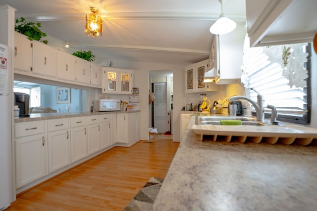 14424 Grenwich Ct, Shelby Twp, MI 48315 - kitchen with white cabinets, light countertops, light wood-style flooring, glass insert cabinets, and under cabinet range hood