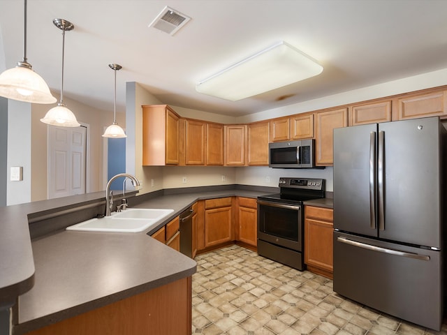 kitchen featuring appliances with stainless steel finishes, a sink, dark countertops, hanging light fixtures, and a peninsula