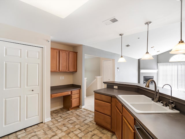 kitchen with a sink, dark countertops, stone finish floors, and decorative light fixtures
