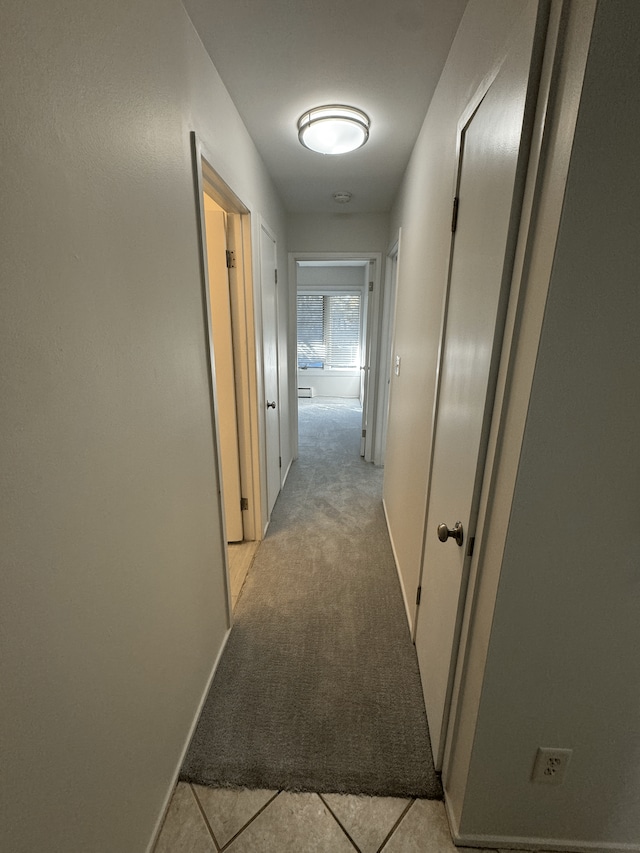 corridor with light carpet, light tile patterned floors, and baseboards