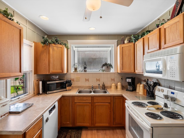 kitchen with white appliances, a sink, light countertops, and backsplash
