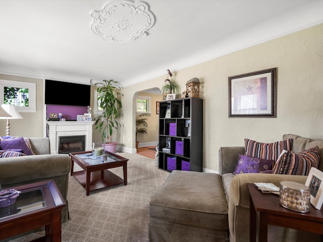 living area featuring arched walkways, a glass covered fireplace, and baseboards