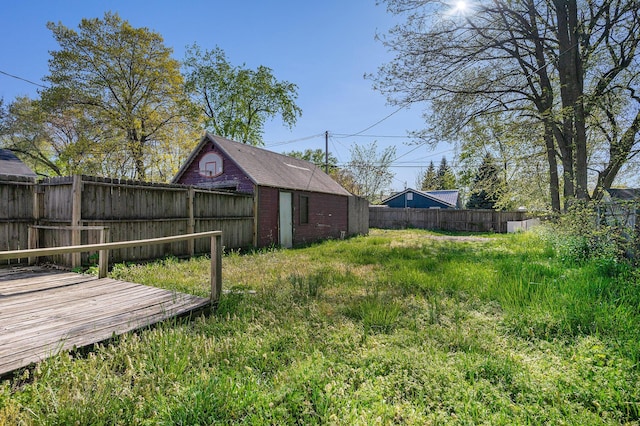 fenced backyard featuring a wooden deck and an outbuilding