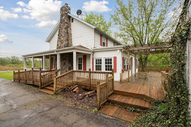 view of front facade with a chimney, a pergola, and a wooden deck