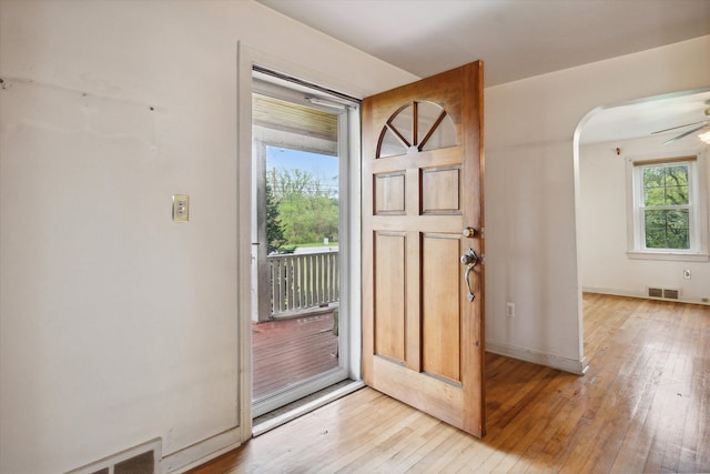 entrance foyer with light wood-style flooring, arched walkways, ceiling fan, and baseboards
