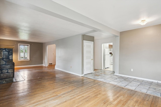 unfurnished living room featuring hardwood / wood-style flooring and baseboards