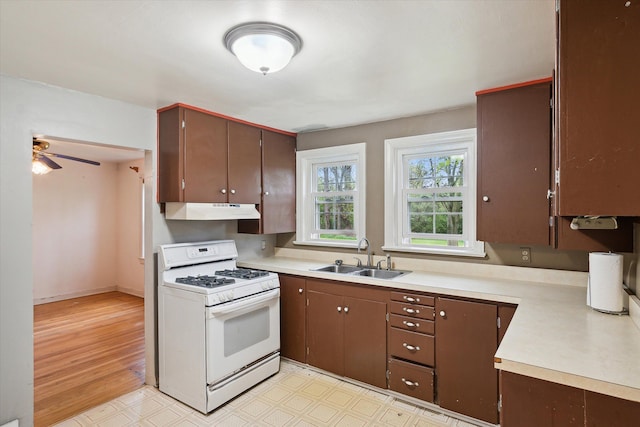 kitchen with gas range gas stove, a sink, under cabinet range hood, light countertops, and light floors