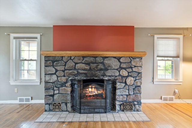 detailed view of wood finished floors, a stone fireplace, and baseboards