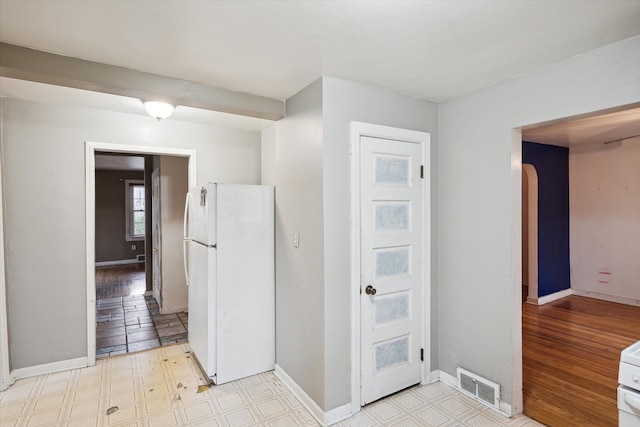 corridor featuring arched walkways, baseboards, and light floors