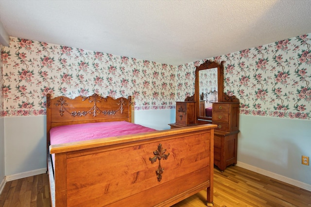 bedroom featuring wallpapered walls, wood finished floors, and baseboards