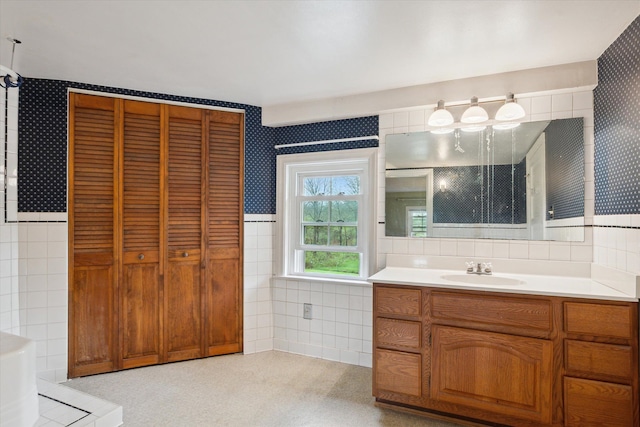 bathroom with tile walls, wallpapered walls, and vanity