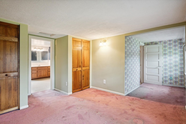 spare room with light colored carpet, wallpapered walls, and baseboards