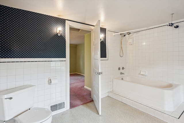 bathroom with toilet, tile walls, and bathing tub / shower combination