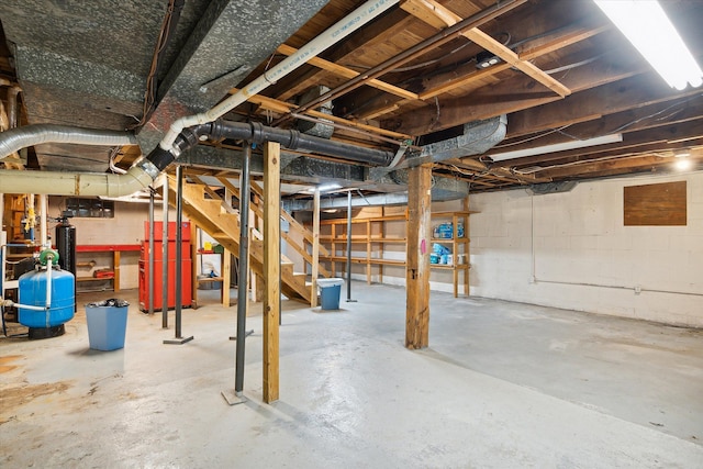unfinished below grade area featuring stairs, a water pressure tank, and concrete block wall