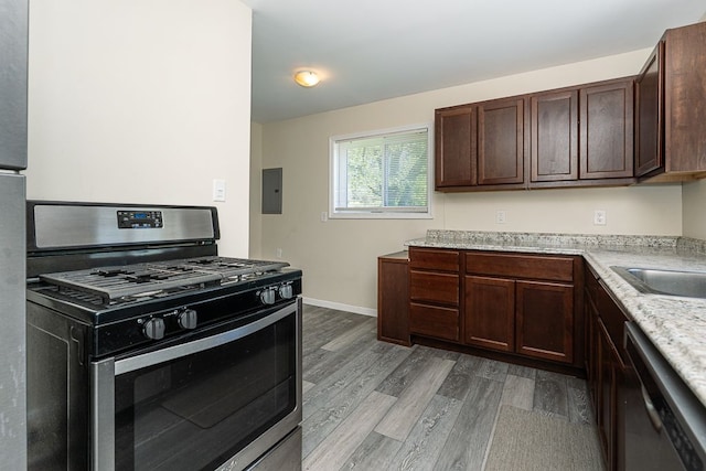 kitchen featuring appliances with stainless steel finishes, wood finished floors, dark brown cabinets, electric panel, and baseboards