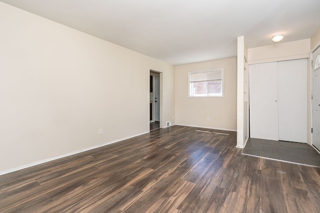 unfurnished bedroom featuring dark wood finished floors, a closet, and baseboards