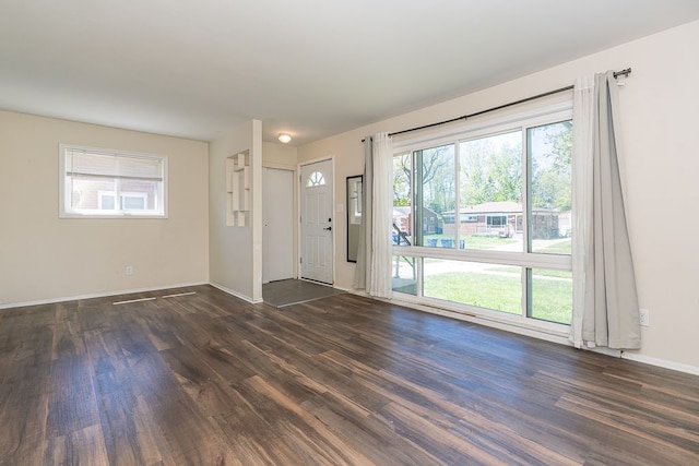 unfurnished living room with dark wood-style flooring and baseboards