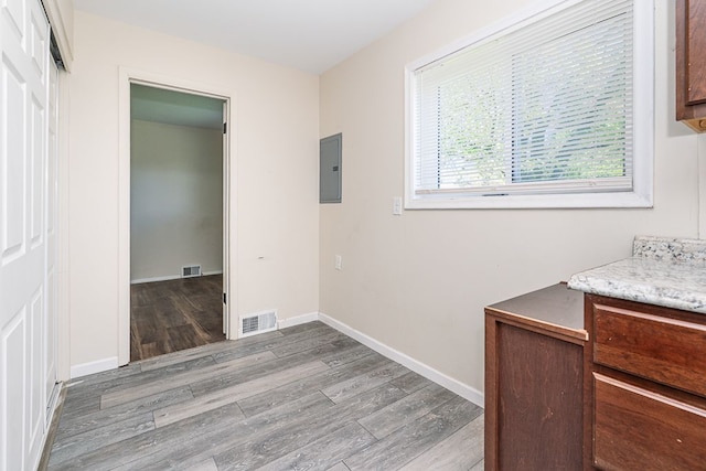 hallway featuring electric panel, wood finished floors, and baseboards