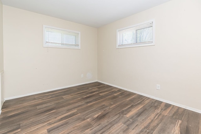 empty room with dark wood-type flooring and baseboards