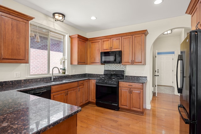 58651 Glacier Club Dr, Washington, MI 48094 - kitchen featuring black appliances, a sink, arched walkways, light wood-style flooring, and brown cabinets