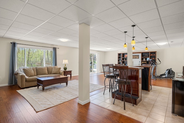 58651 Glacier Club Dr, Washington, MI 48094 - living area featuring a paneled ceiling, light wood-type flooring, baseboards, and a bar