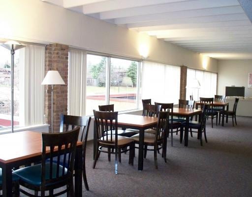 dining space with carpet and beamed ceiling