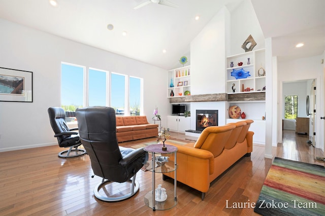 12250 Knoper Ct, Allendale, MI 49401 - living area featuring vaulted ceiling, wood-type flooring, a glass covered fireplace, built in shelves, and baseboards